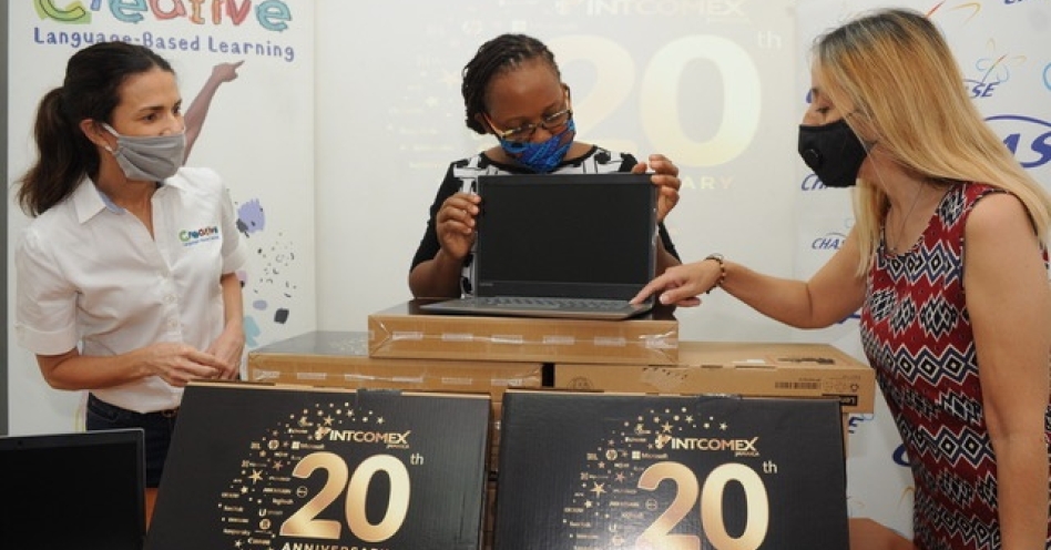 Mandy Melville (left), CLBL Foundation and Claudia Bermudez (right), sales manager, Intcomex Jamaica look on as Natalie Bennett, teacher at New Providence Primary School, excitedly examines one of the laptops donated by Intcomex Jamaica. (Photo: Contributed)