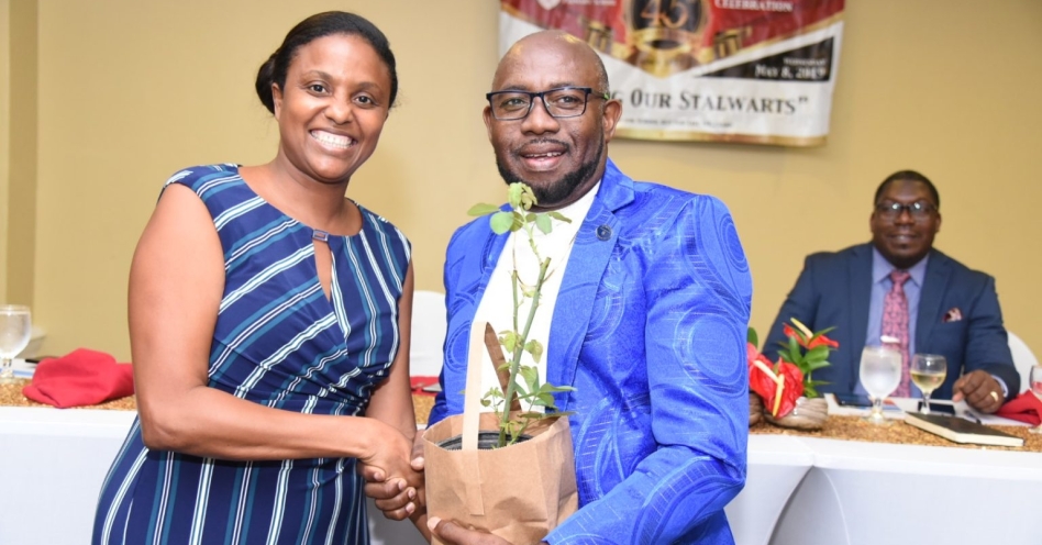 Chairperson, Early Childhood Commission, Trisha Williams-Singh (left) hands over a plant from her garden to Principal, Horizon Park Primary and Infant School, Lloyd Bennett, at Horizon Park Primary and Infant School’s Retirees Appreciation Banquet, held at The Knutsford Court Hotel recently. (JIS Photo)