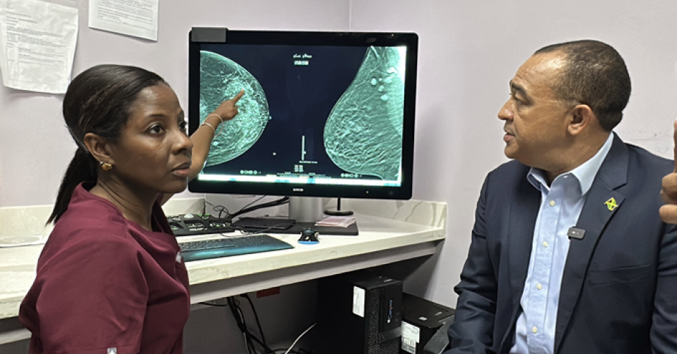 Minister of Health and Wellness, Dr. the Hon. Christopher Tufton, MP (right) looks on as Cancer Imaging Radiologist, Dr. Michelle Bremmer (left) shows a three dimensional breast image generated by a Tomosynthesis machine at the UHWI Women's Imaging Centre during a tour of the facility on Monday (May 5). The advanced technology is used in breast cancer screening and diagnosis.