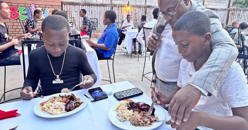 Obryan Leighton guides Jauqueem Lewin how to properly use knife and fork at the Life of Love Football Academy’s inaugural dinner and award ceremony at Kaluga Kafe, Old Harbour on Saturday, May 31, 2025. Also in the picture is Shemario Smith. (Photo: Alexia King-Whyte)