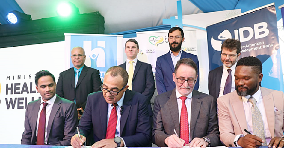 Dr. the Hon. Christopher Tufton (second from left) and Dr. John Parry (second from right), Clinical Director of the UK firm, The Phoenix Partnership (TPP) sign the agreement for the implementation of the Electronic Health Records System to Jamaica. Sharing in the occasion at the Spanish Town Hospital on Tuesday, February 28 are Mr. Tariq Alli (seated left), IDB Group General Manager Country Department Caribbean Group and Country Representative in Jamaica; and Mr. Orett Clarke, Programme Manager for the Health Systems Strengthening Programme (HSSP) of the Ministry of Health & Wellness. They are joined by (standing from left) Dr. David Jemmott, EHR Lead, HSSP; Mr. Ashley Brook, Director at TPP; Mr. Anton Ilarionov, Component 2 Lead, HSSP; and His Excellency Daniel Shepherd, Deputy British High Commissioner to Jamaica.